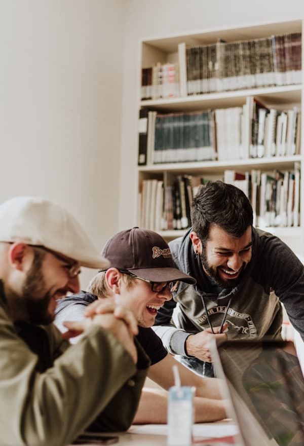 Three students laughing as they look at a screen together